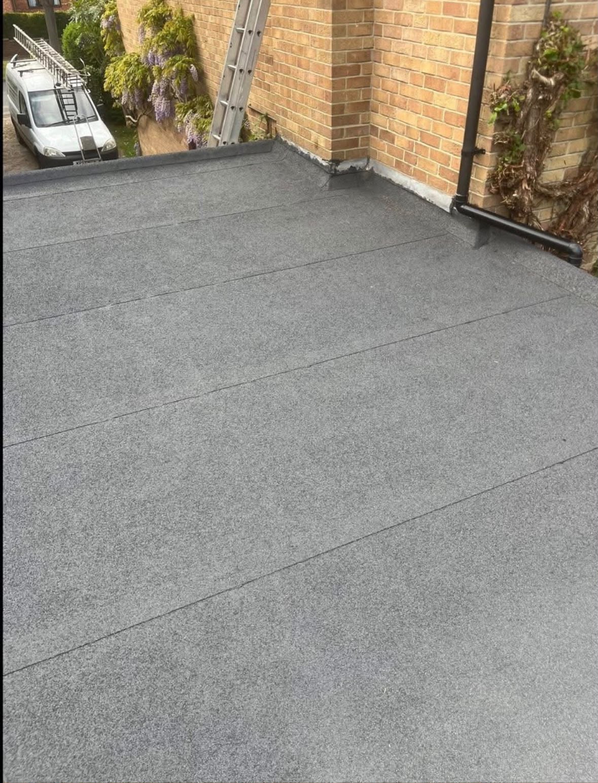 Flat roofing surface adjoining a brick wall
