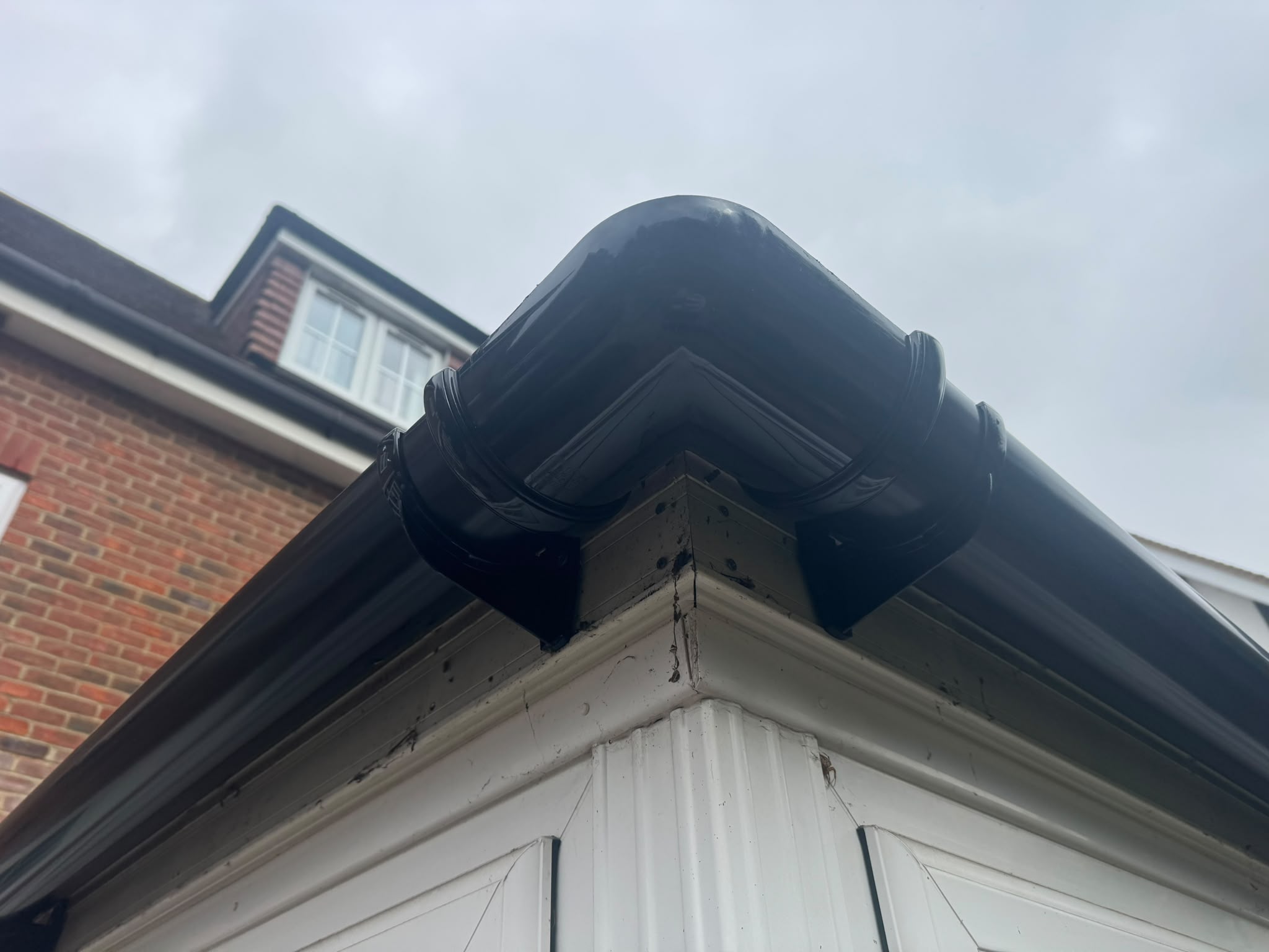 Dark gutter corner and fascia at a roof edge